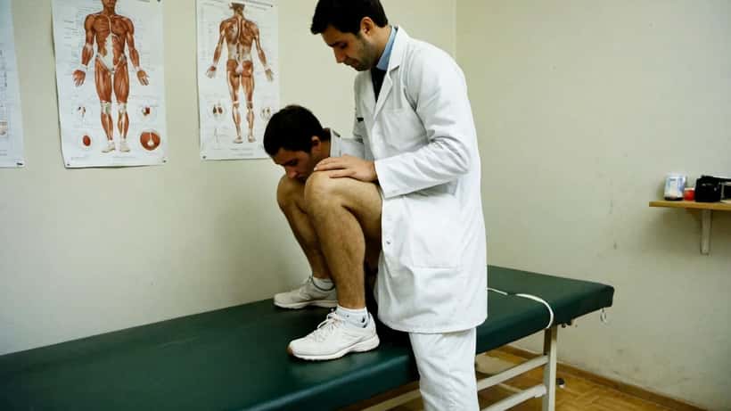 Médico de medicina desportiva a examinar joelho de tenista numa clínica em Lisboa