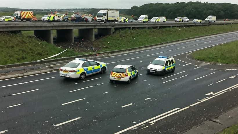 Emergency vehicles and police tape at a multi-vehicle motorway crash scene in England