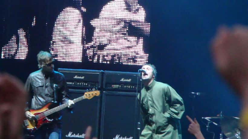 Oasis em show ao vivo no estádio, Liam Gallagher ao microfone cantando Wonderwall para uma multidão