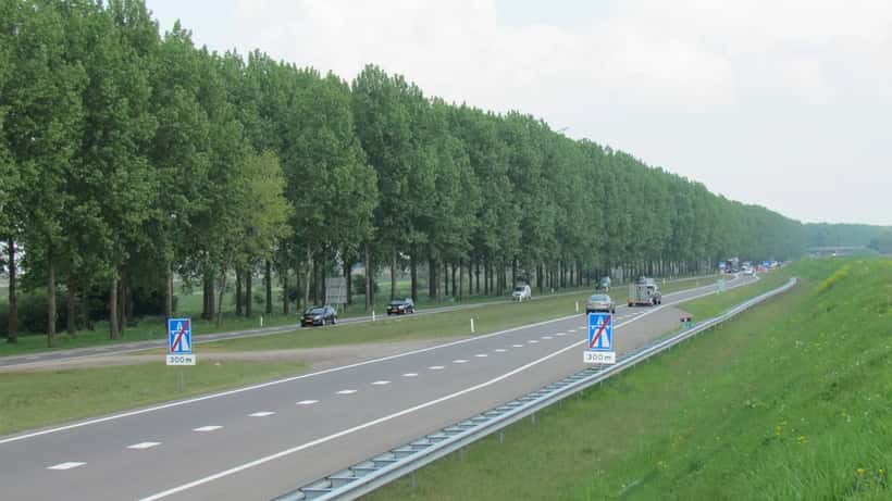 A15 snelweg bij Bemmel, Nederland — druk vrachtverkeer langs woonwijken