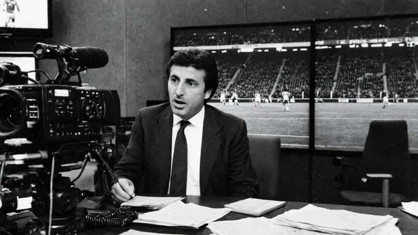 Giornalista sportivo italiano in studio televisivo durante un dibattito acceso su un programma calcistico