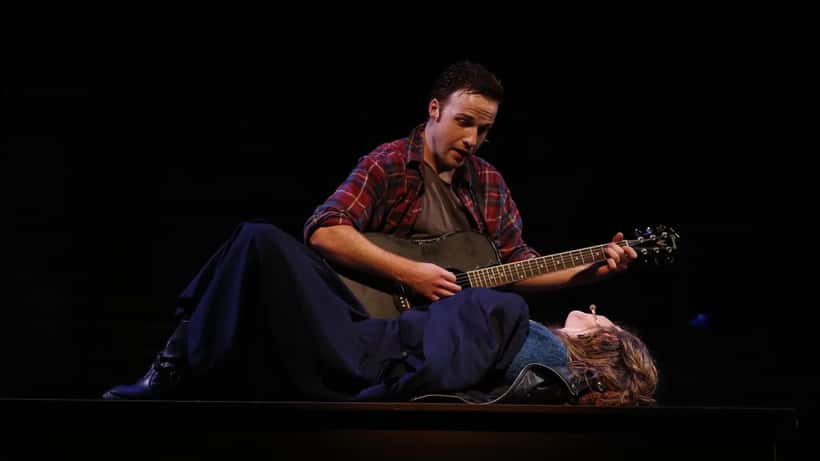 Scene from a stage production of Rent musical, performers on stage in ensemble number