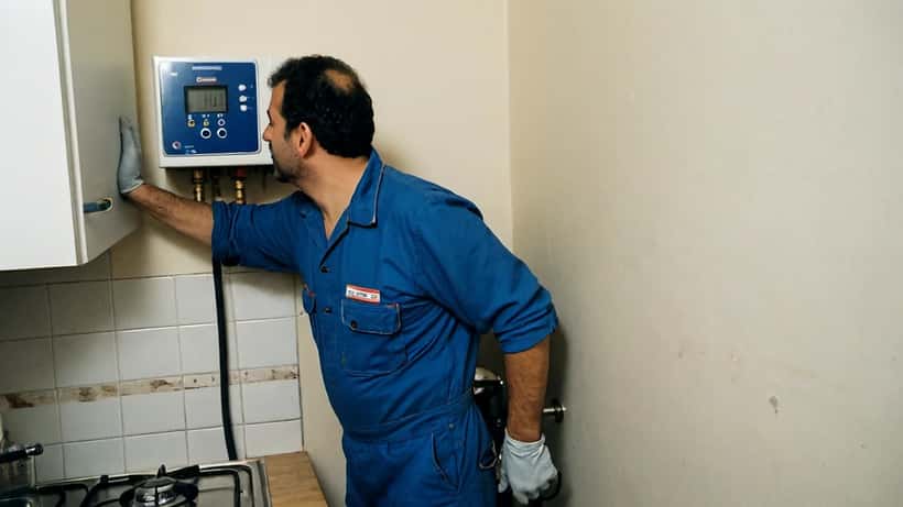 Idraulico italiano ispeziona una caldaia a gas in un appartamento di Milano con manometro digitale