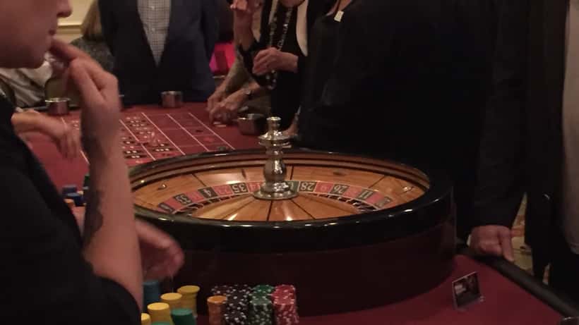 People at casino tables during a casino night event with chips and gaming tables