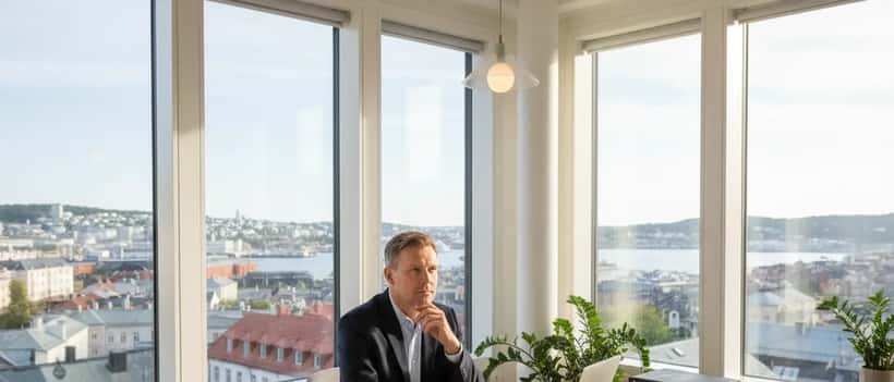 Norsk advokat i mørk blazer ved skrivebordet i et Oslo-kontor med skandinavisk dagslys