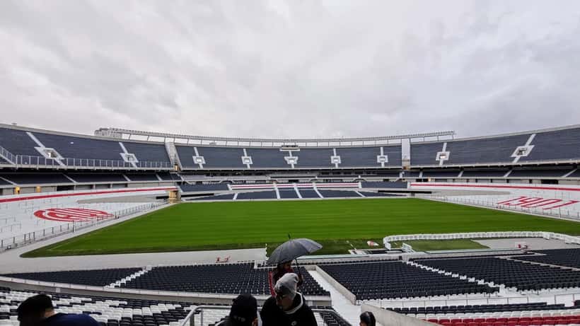 Estádio de futebol argentino com gramado e arquibancadas ao fundo