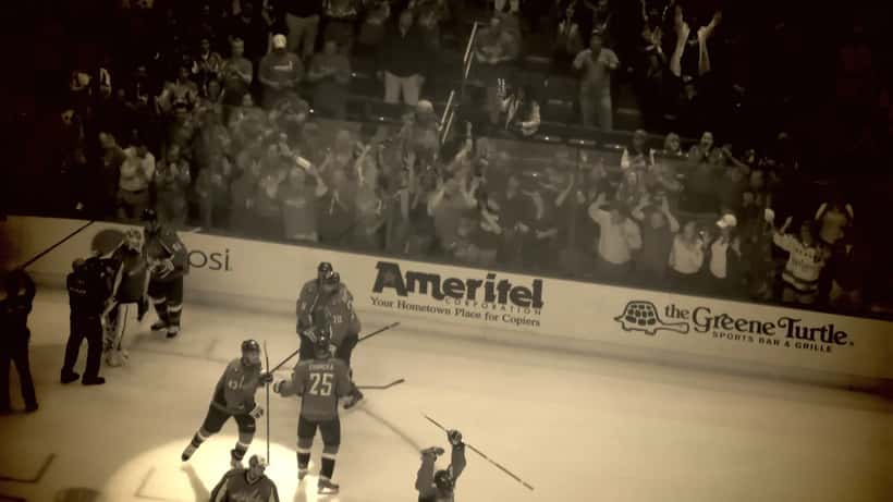 Jugadores de hockey sobre hielo durante un partido de playoffs de la NHL con las gradas llenas de aficionados