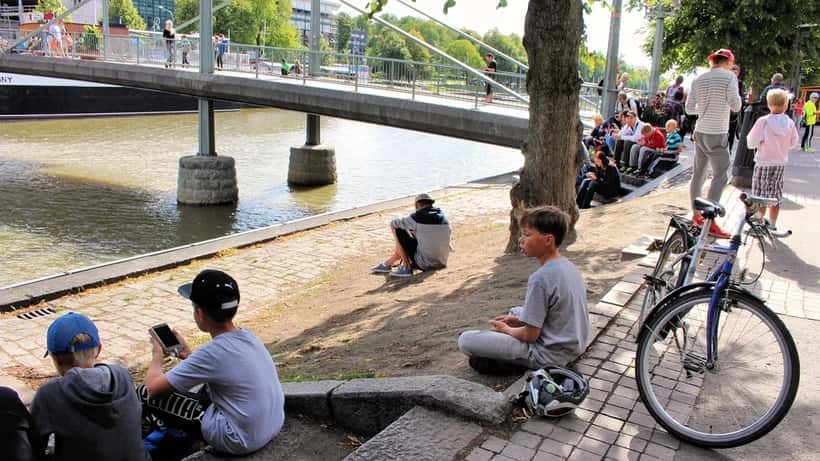 Pessoas jogando Pokémon GO em parque, segurando smartphones durante caça de Pokémons
