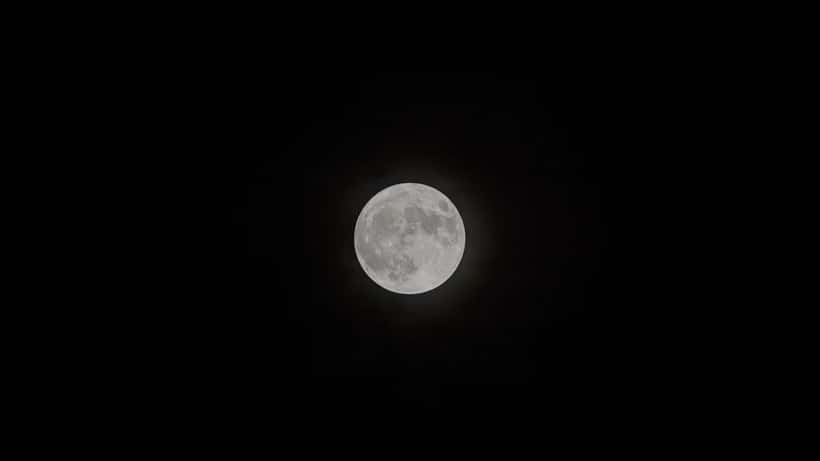 Full moon rising in July 2026, bright and round against a dark sky