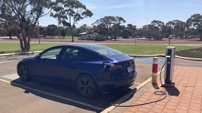 Tesla Model 3 connecté à une borne de recharge AC dans un stationnement