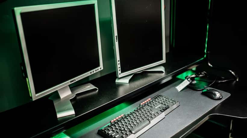 Gaming-Setup mit Dual-Monitor, Tastatur und Maus in einem abgedunkelten Spielzimmer