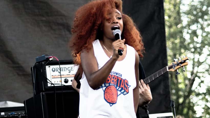 SZA performing on stage at a music festival, vintage-inspired outfit