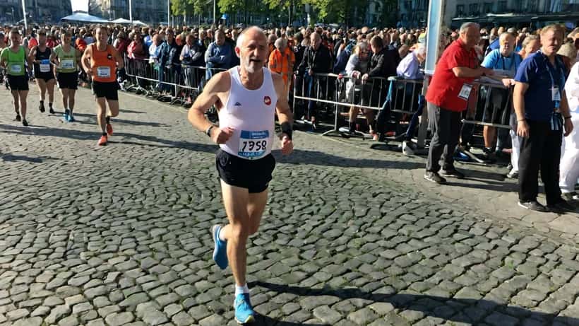 Coureur franchissant la ligne d'arrivée du Marathon de Zurich 2026 avec des bénévoles médicaux en arrière-plan