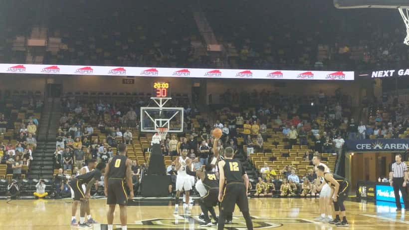 Basketball players competing during a college game tipoff, press photo documentary style
