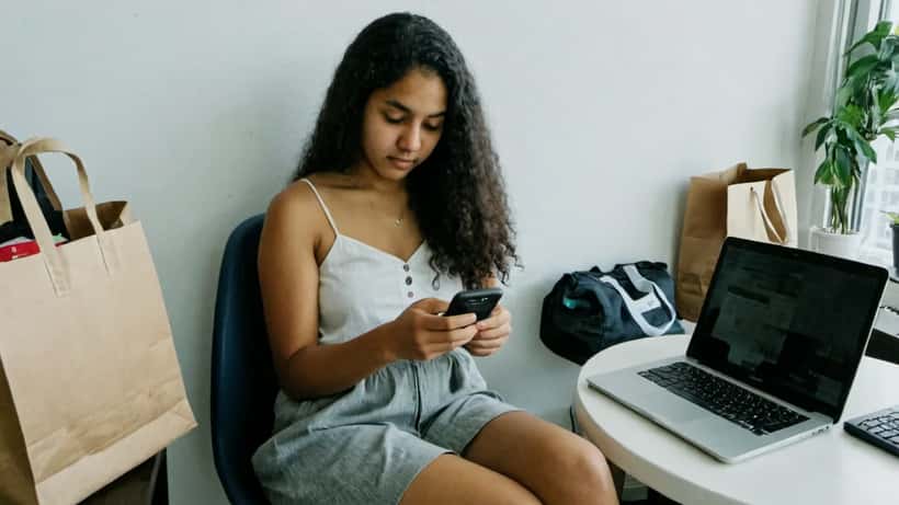 Young woman in Toronto apartment shopping online for limited edition fashion on her phone