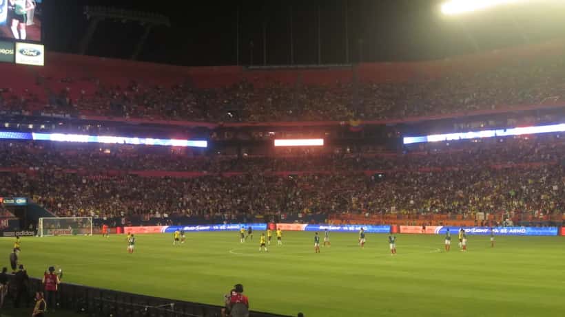Mexico and Colombia football players competing in an international friendly match at a stadium