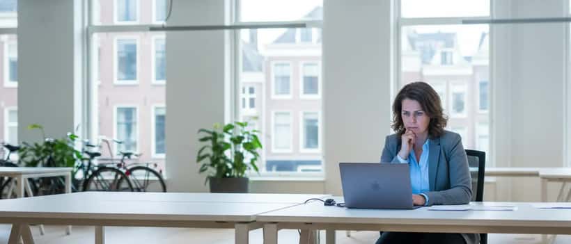 Nederlandse kantoormedewerker bekijkt bezorgd laptop na aankondiging Unilever reorganisatie 2026