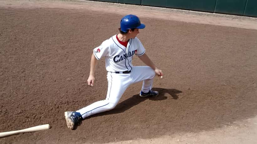 Young baseball player stretching for first base and twisting his ankle on a Canadian diamond in April 2026