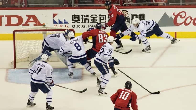 Toronto Maple Leafs and Washington Capitals players competing on ice during an NHL game at an indoor arena