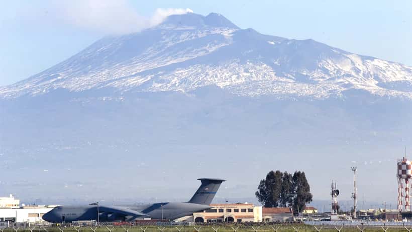 La base militare di Sigonella in Sicilia con l'Etna sullo sfondo e un aereo da trasporto militare americano C-5 in pista