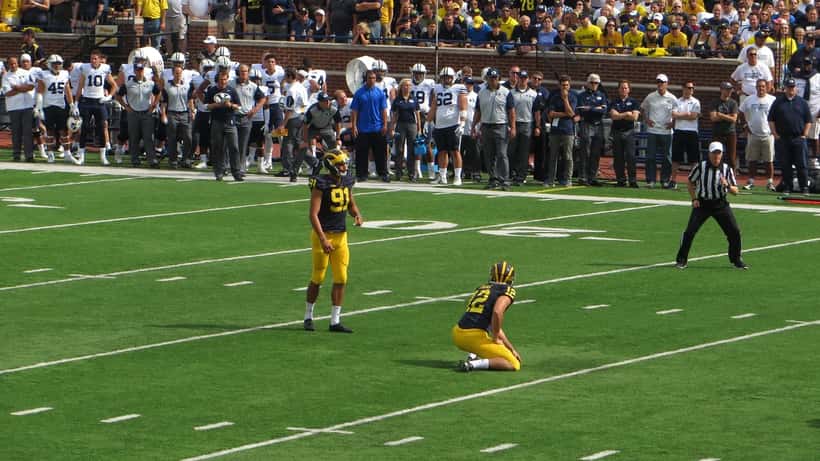 College football placekicker preparing for a field goal attempt at Michigan Stadium