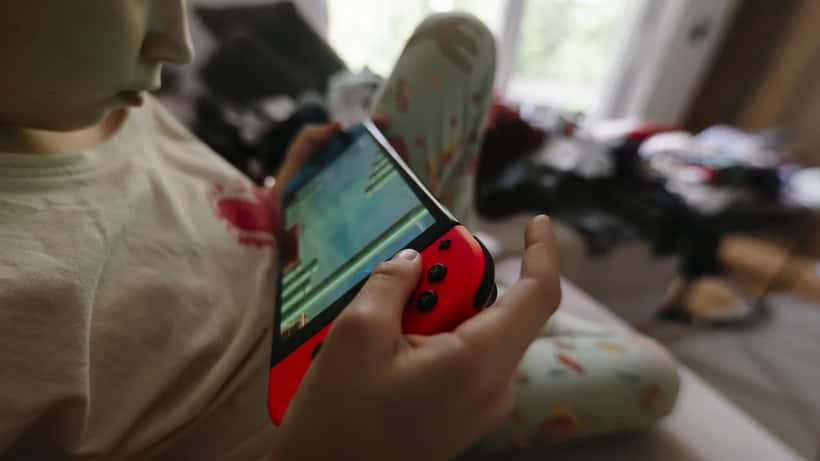 Enfant jouant à une console Nintendo Switch assis sur un canapé