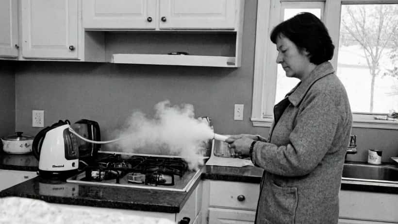 Femme examinant un aspirateur vapeur Bissell rappelé dans une cuisine canadienne