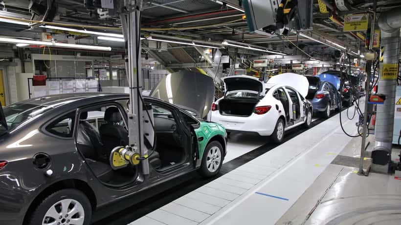 Car assembly line at European automotive factory with workers on production floor