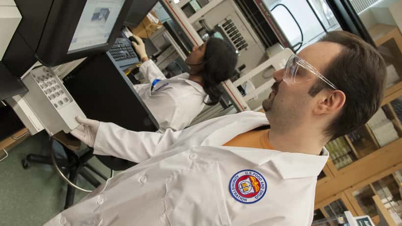 Laboratorio di sicurezza alimentare con tecnici che analizzano campioni di cibo per la ricerca della salmonella