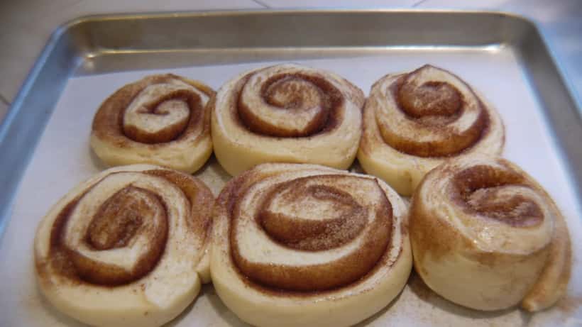 Färska kanelbullar på ett bakplåt inför Kanelbullens dag