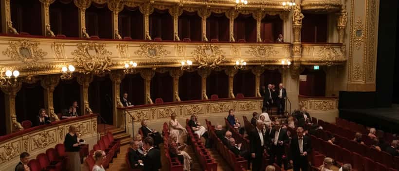 Elegantes Opernhaus-Interieur mit roten Samtsitzen und goldenen Balkonen, Publikum nimmt Platz
