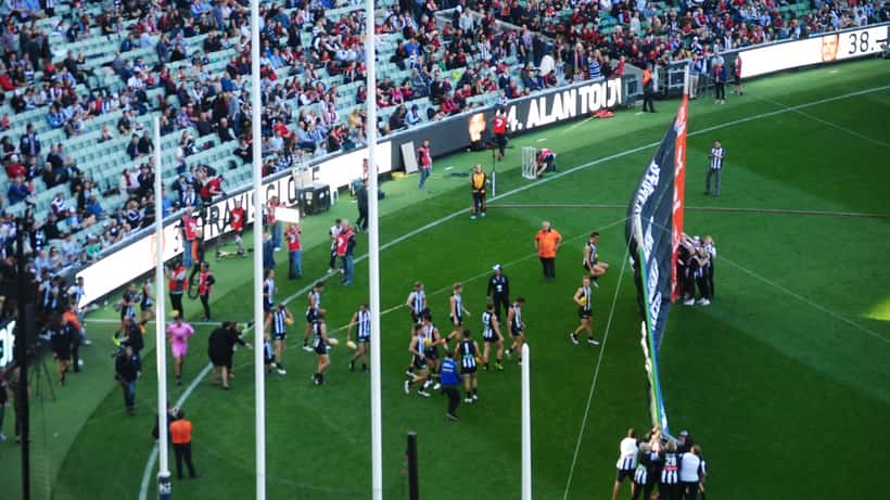 AFL players running through paper banner at match
