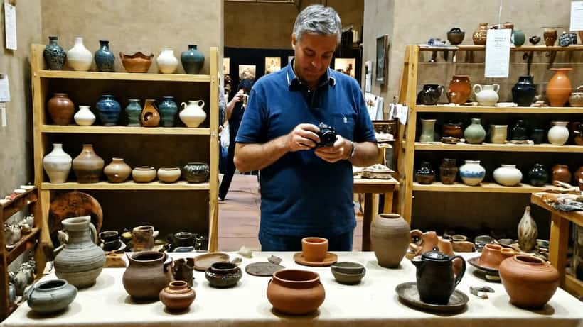 Artigiano italiano che mostra prodotti in ceramica e cuoio al proprio stand durante una fiera dell'artigianato a Firenze, stile fotoreportage documentario