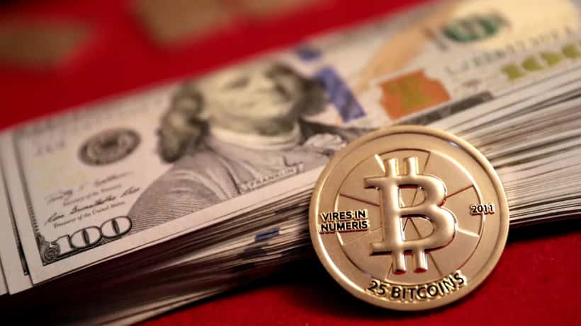 Bitcoin Casascius Goldmünze mit US-Dollar-Scheinen – Symbolbild für Kryptowährung und Investition
