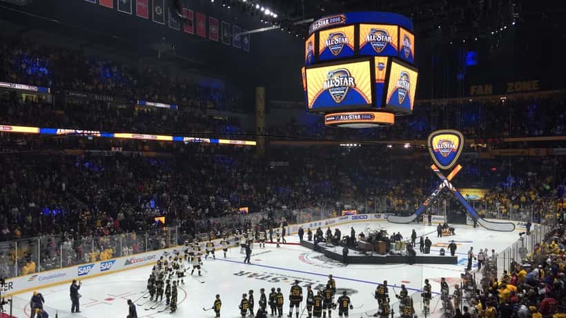 Ice hockey players competing in an NHL All-Star game on an indoor rink