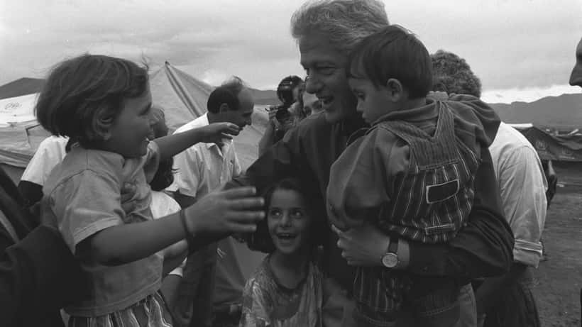 Bill Clinton begroet Kosovaarse vluchtelingen, symbool van internationale solidariteit en filantropie