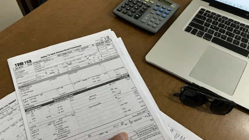 Accountant reviewing IRS tax forms and Schedule 1-A documents at desk