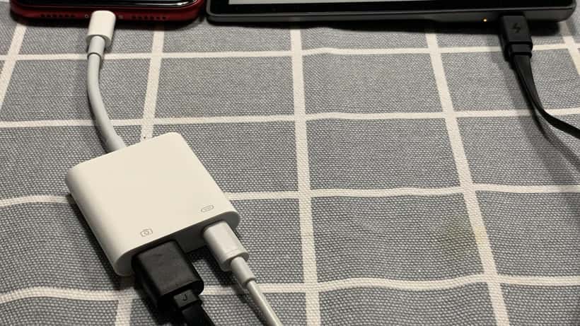 iPhone em cima de uma mesa com ecrã ligado, ao lado de um kindle, representando a decisão de atualização de dispositivos