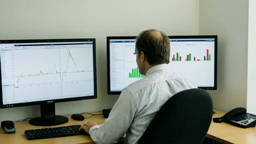 Finansiell rådgivare granskar OMXS30 börsgraf med grön rekyl på datorskärm i Stockholmskontor