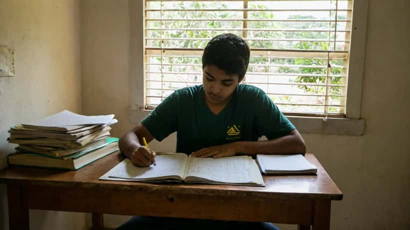 Estudante brasileiro revisando anotações de estudo com professor particular em casa