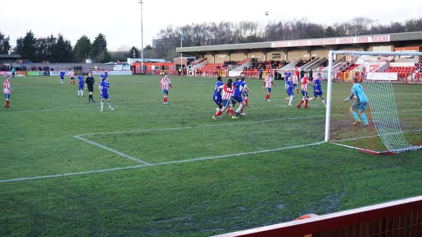 Match de football en Angleterre, tribunes remplies de supporters et joueurs en action sur la pelouse