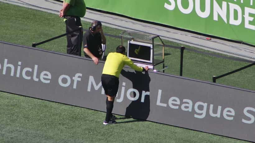 Arbitro consulta il monitor VAR durante una partita di calcio