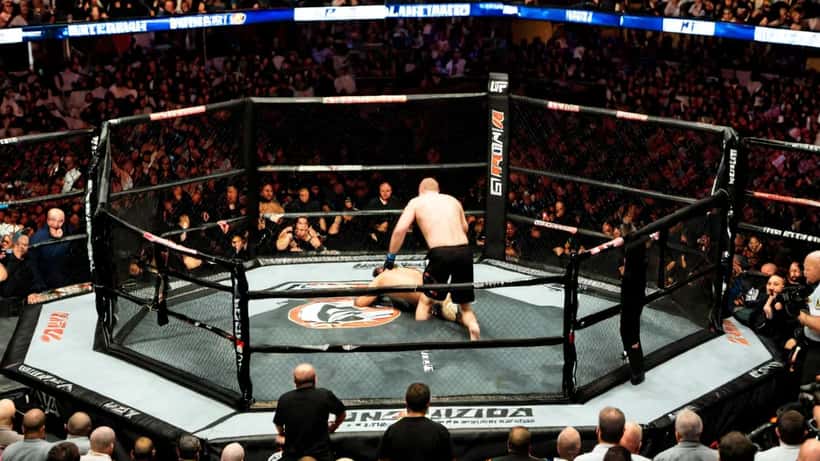 MMA-Kämpfer am Boden nach TKO im UFC-Oktagon, Schiedsrichter greift ein