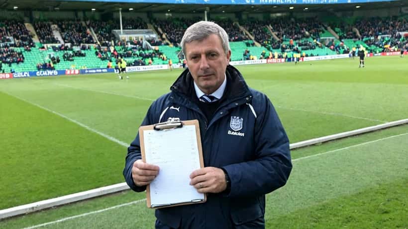 Soccer manager holding tactical clipboard on Championship stadium touchline