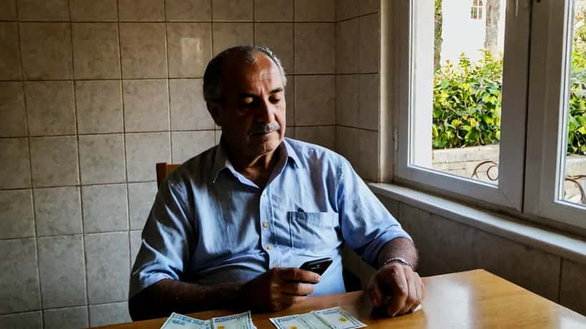 Homem português a segurar bilhete de lotaria Euromilhões na cozinha