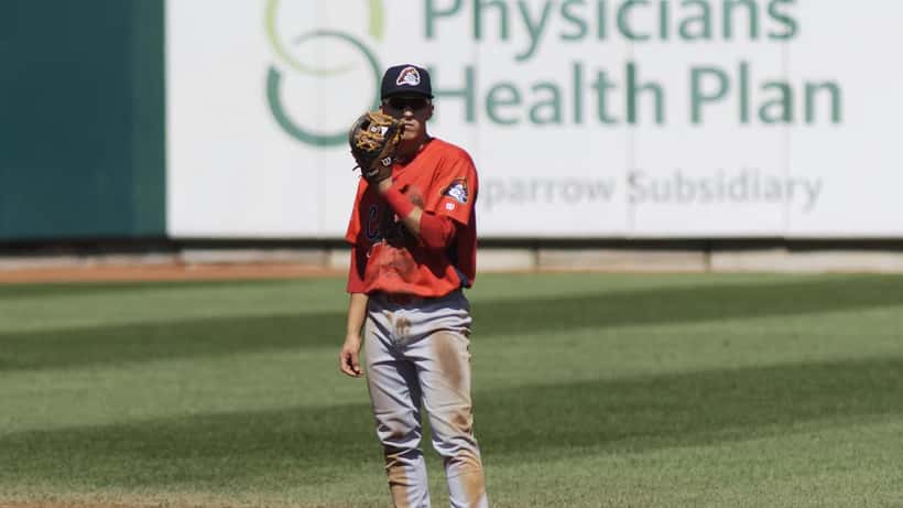 Tommy Edman running the bases in a Cardinals uniform, baseball stadium action shot