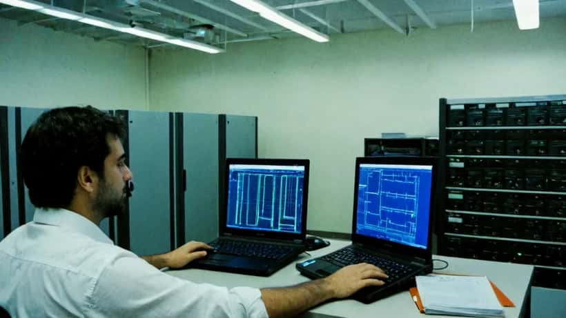 Consulente informatico italiano analizza algoritmi di crittografia post-quantistica su schermo in ufficio a Milano