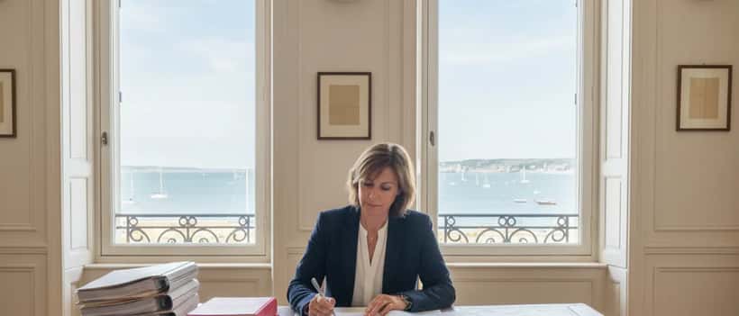 Avocate consultant des documents juridiques dans un bureau normand face à la baie de Granville