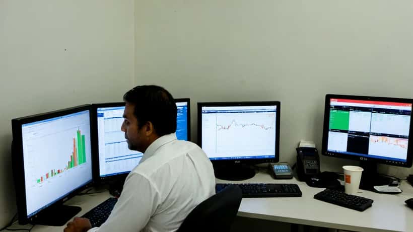 Analista financeiro brasileiro examinando gráficos de câmbio dólar-real em ambiente de trabalho moderno em São Paulo