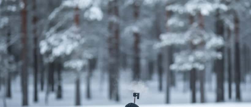 Biathlet in Winterausrüstung liegt im Schnee und zielt mit dem Gewehr auf das Ziel